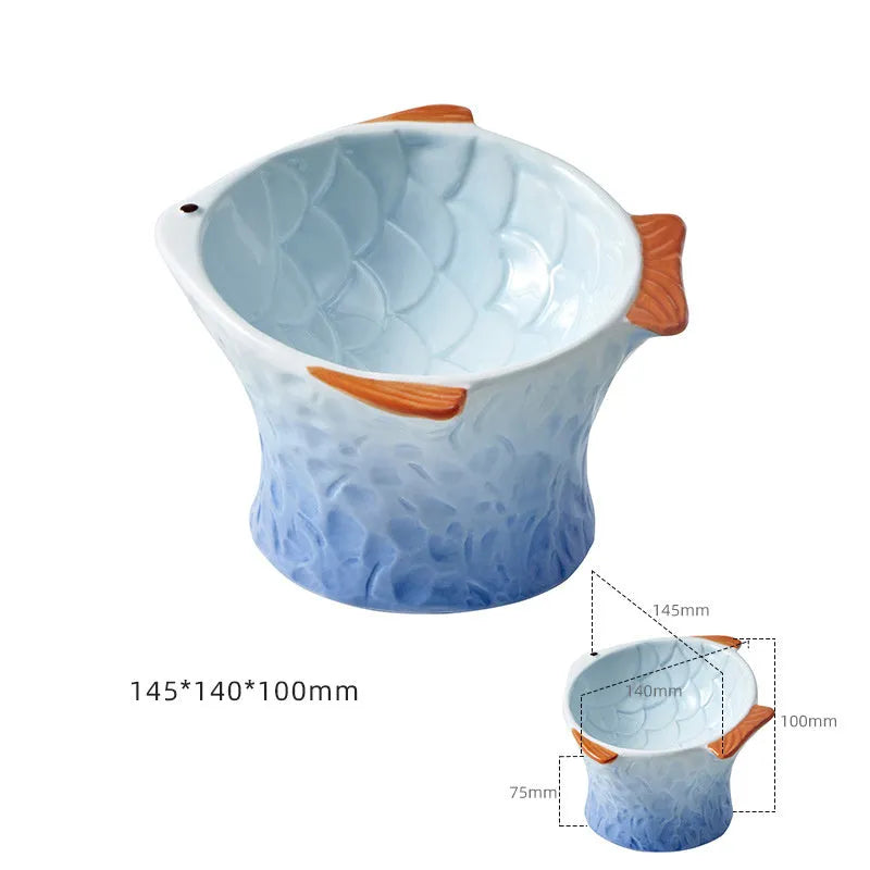 Blue ceramic cat food bowl in a fish shape with a tilted, elevated design and non-slip base.