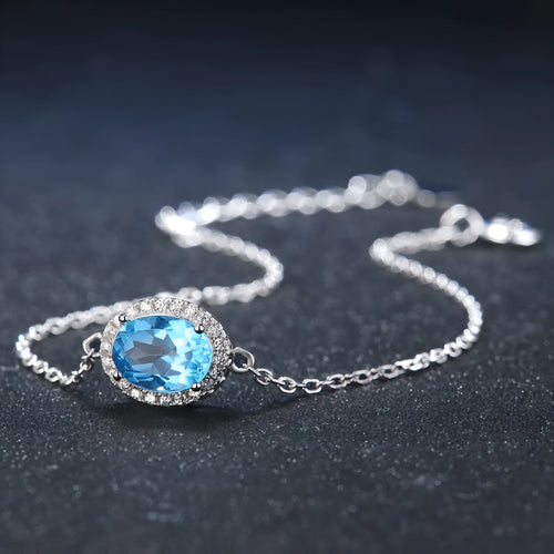 Women's sterling silver jewellery set with blue topaz stones, showing geometric earrings, necklace, ring, and pendant.