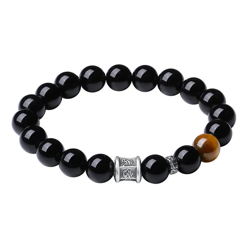 Men's black obsidian and silver bracelet with a 10mm prayer wheel charm on a dark background.
