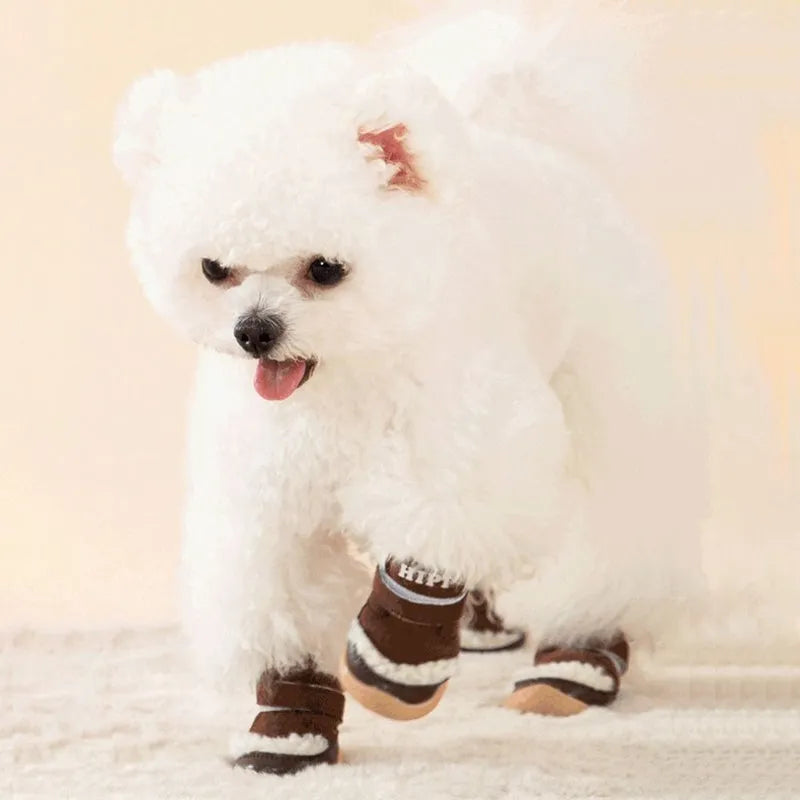 Brown winter dog shoes with adjustable Velcro straps and anti-slip rubber soles on a snowy surface