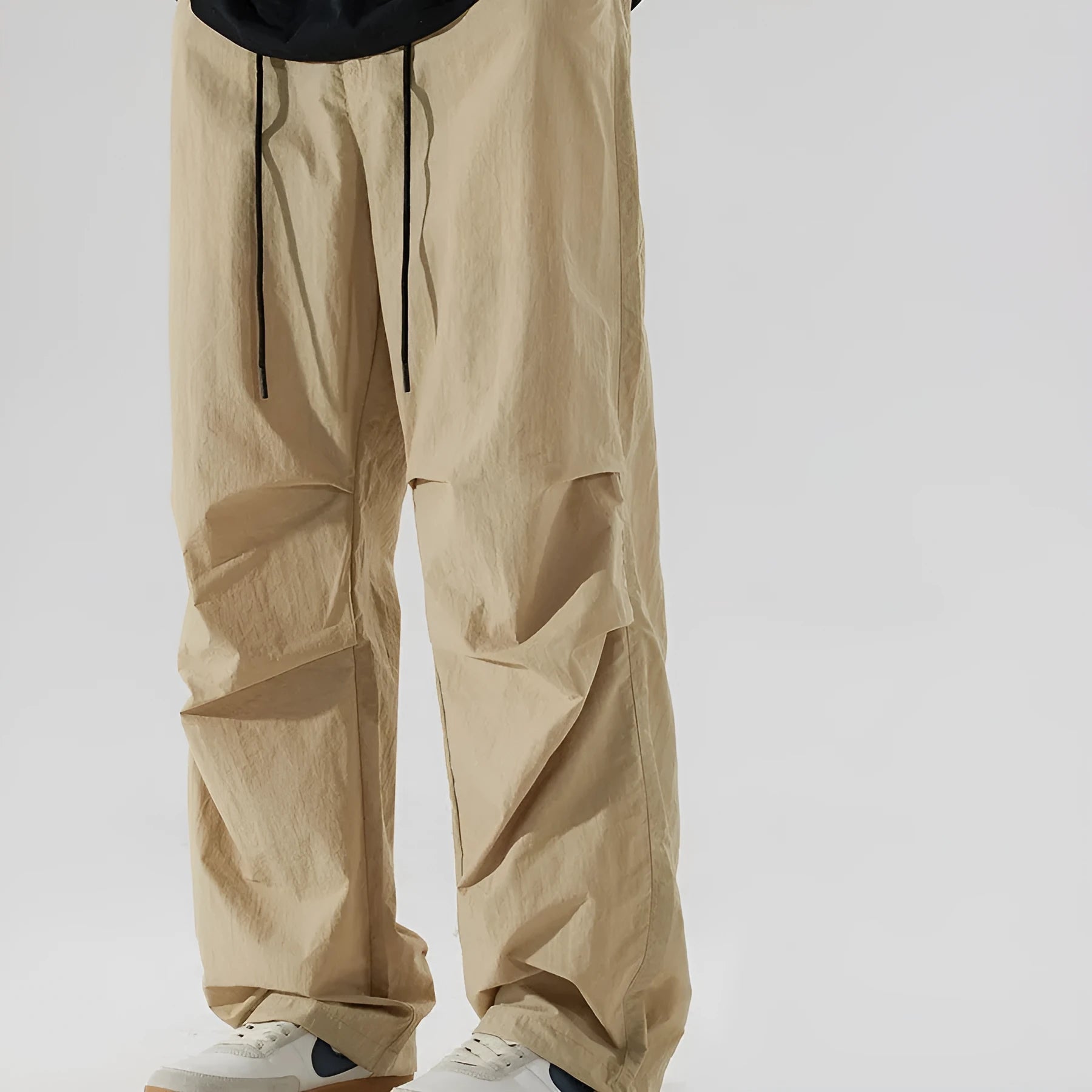 Man wearing loose straight leg casual trousers in lightweight nylon fabric, available in multiple colours.