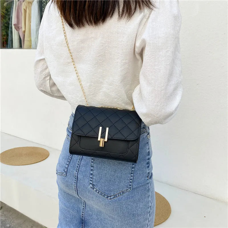 Women's black PU leather crossbody bag with diamond lattice chain detailing and adjustable shoulder strap