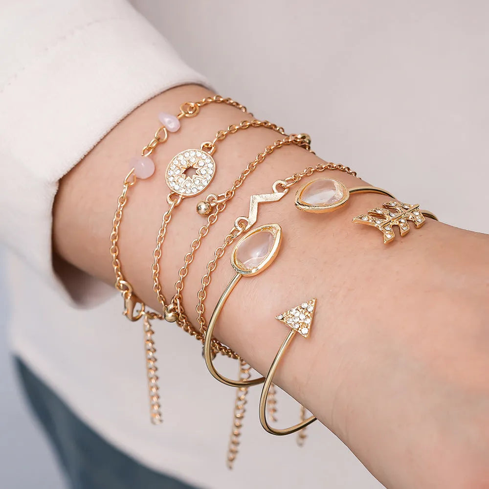 Set of six gold fashion bracelets with water droplet, arrow, V-shape and drill designs.