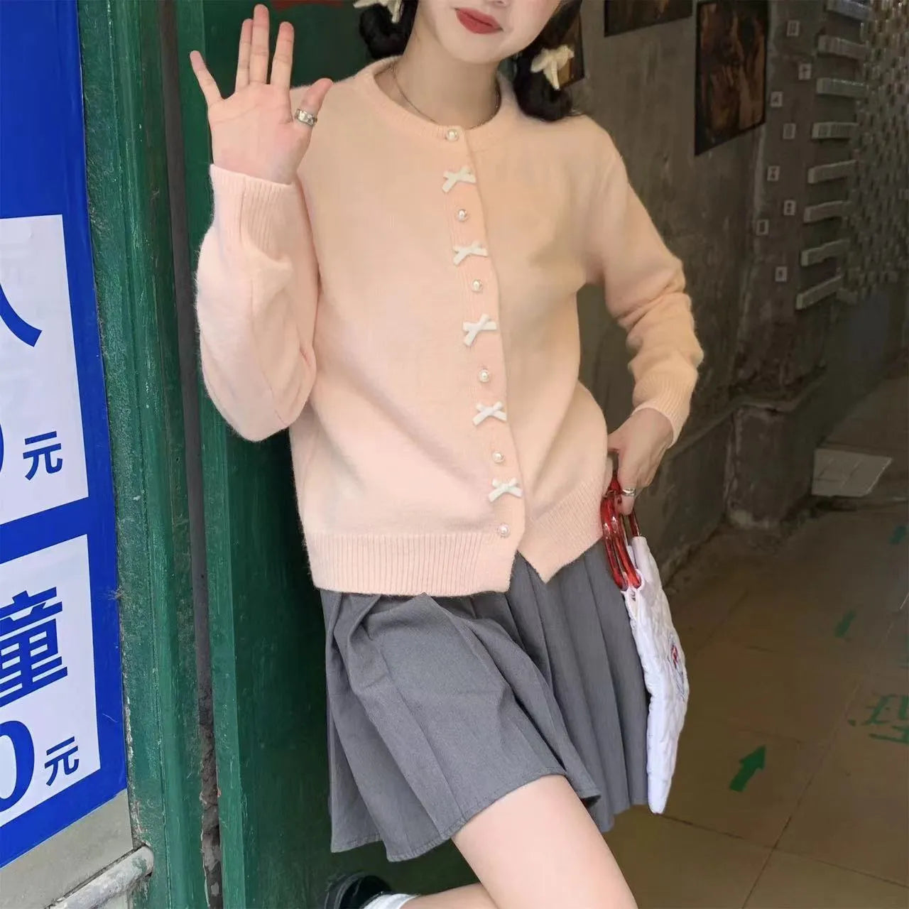 Women's light yellow cashmere acrylic cardigan with pearl buttons and a bow on the front.