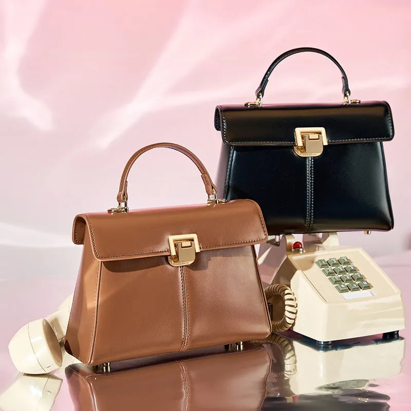Women's black leather shoulder bag with vachette clasp showing horizontal square shape and adjustable strap