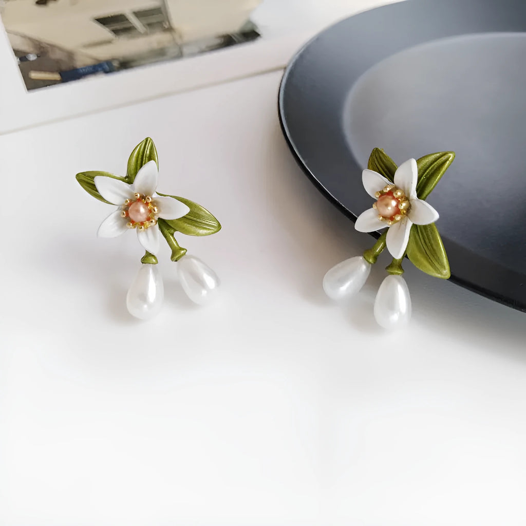 Women's alloy flower earrings with needle camellia design in sterling silver colour, shown as clip-on and ear stud styles
