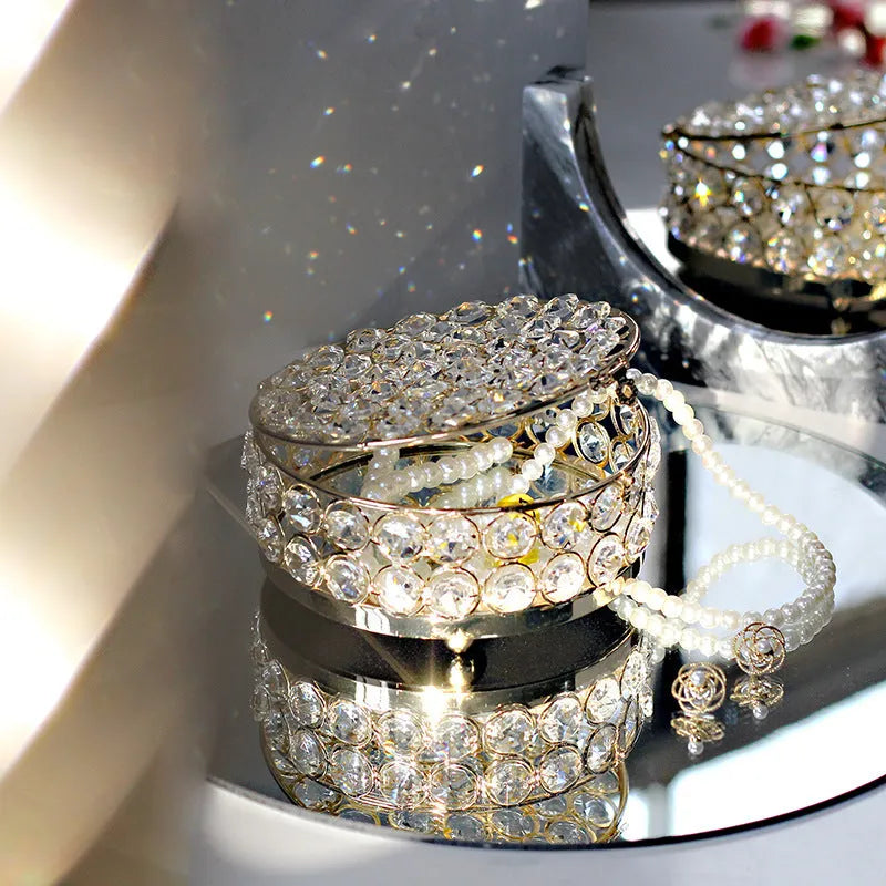French gold iron jewellery box with a clear crystal glass lid on a wooden surface.