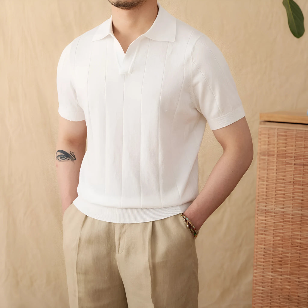 Man wearing a dark blue short sleeve polo shirt with a subtle sunken stripe knit texture and a polo collar.