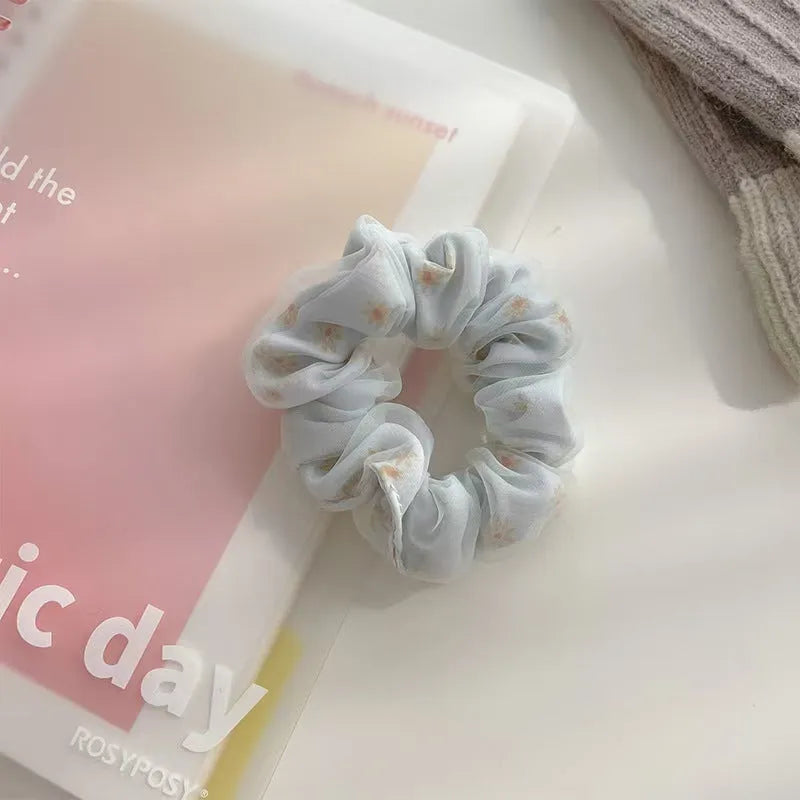 Mesh sense polyester large intestine hair band in milky white, pink, and light blue on a plain background
