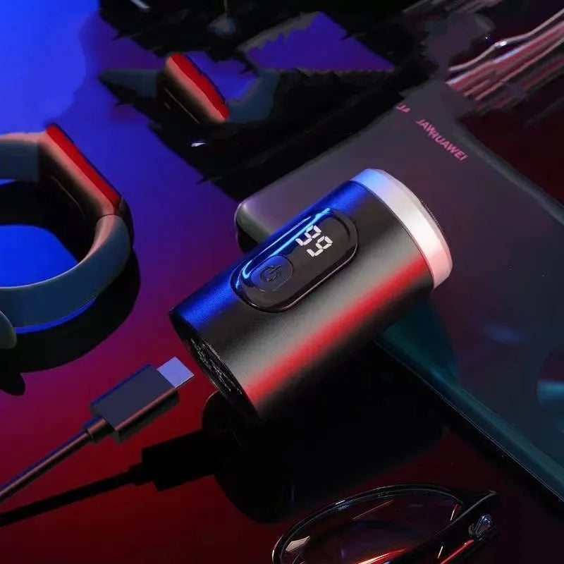 Black portable USB rechargeable shaver with cleaning brush and cable on a table.
