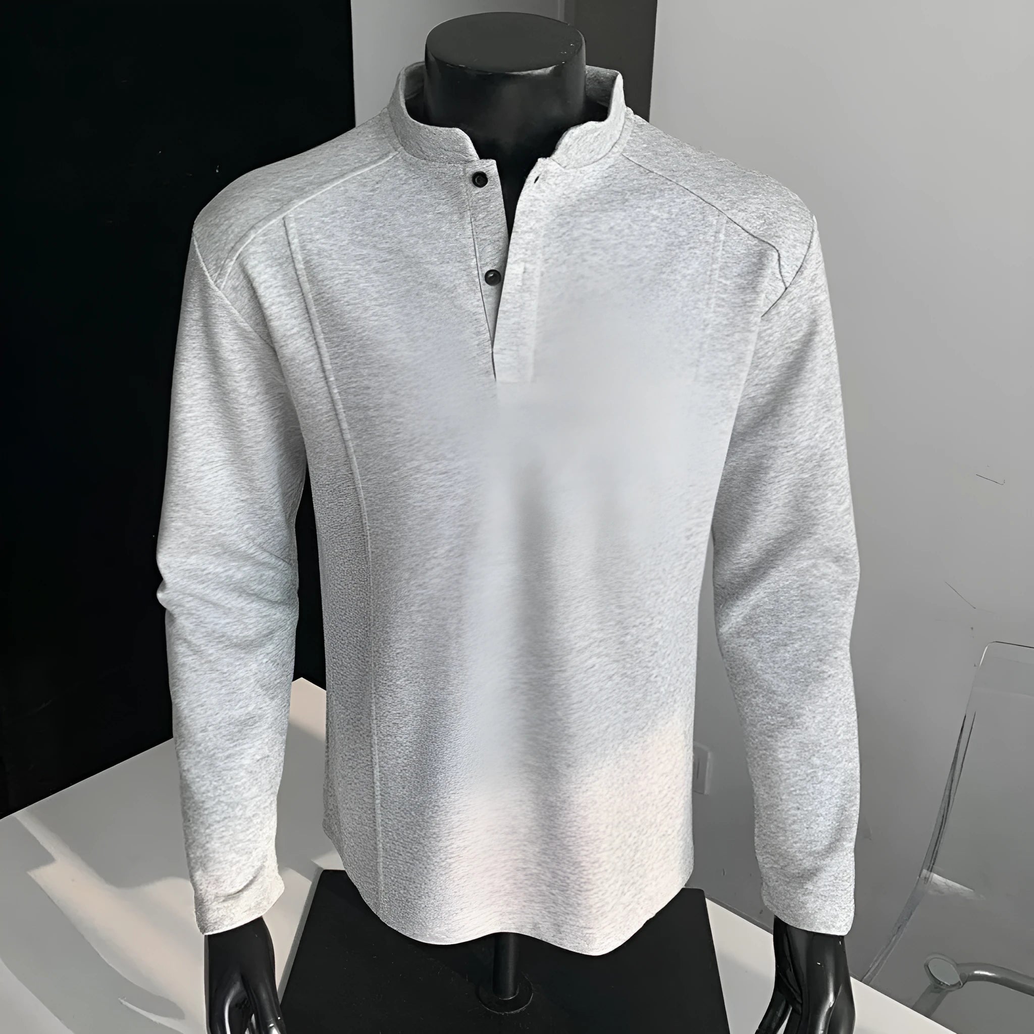 Man wearing a gray long sleeve sweater with a stand-up collar and patchwork design on the shoulders