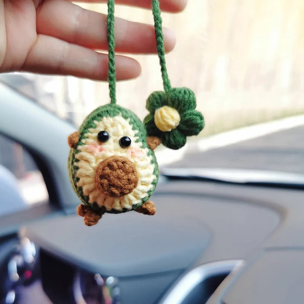Handmade crocheted avocado-shaped car pendant in wool, shown in three colour variations.