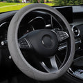 Close-up of a black corrugated elastic steering wheel cover on a car wheel.