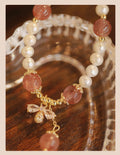 Close-up of a women's hand-strung strawberry quartz crystal bracelet with a decorative bow.