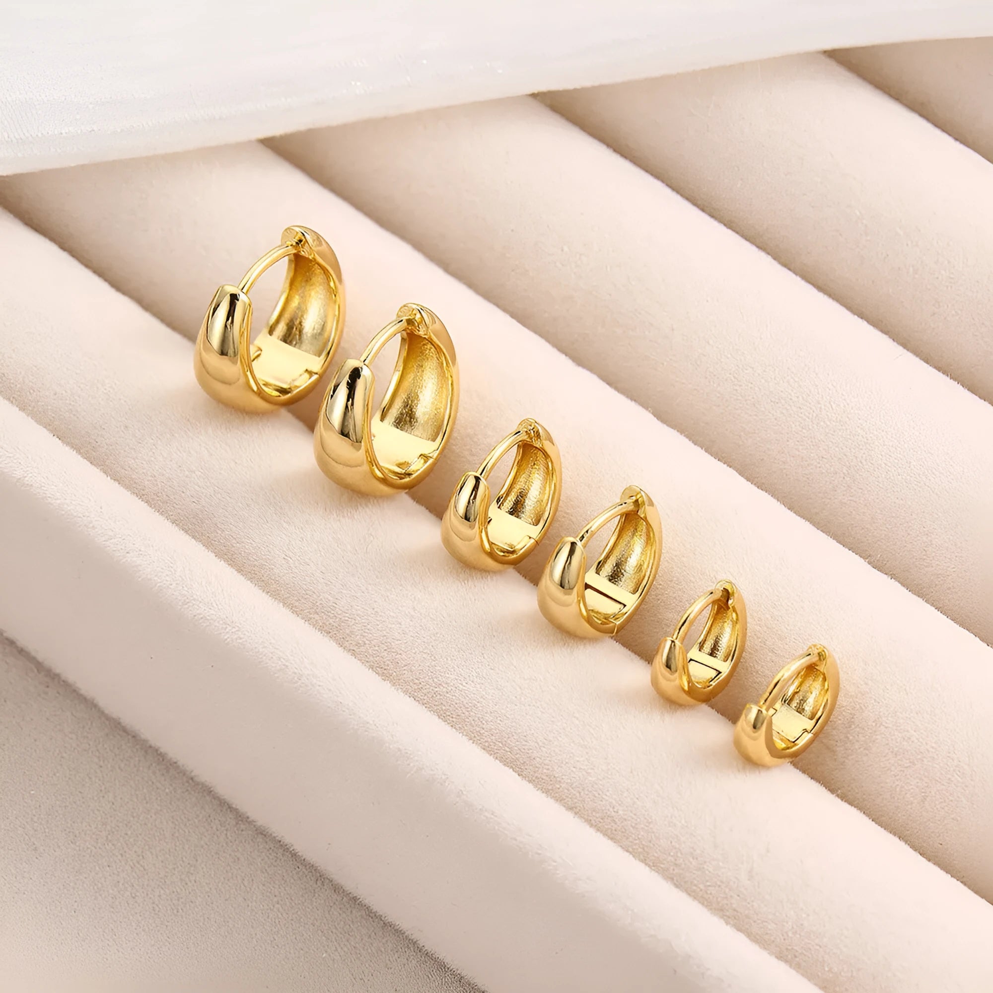 Drop-shaped copper earrings set of three sizes in gold finish on a white background