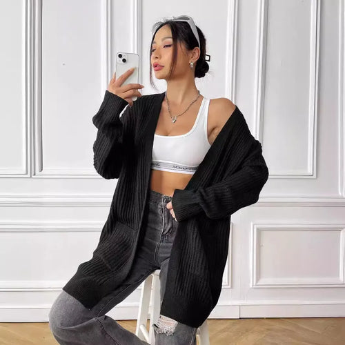 A loose-fitting, mid-length acrylic cardigan sweater in a solid colour, shown in a street hipster style.
