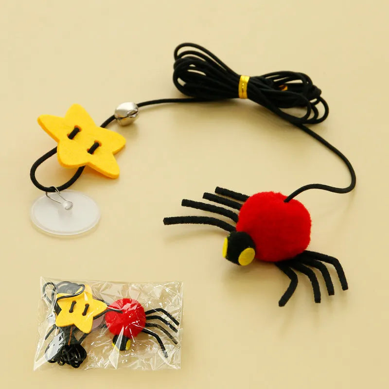 Red and yellow cat toy with feather and bell spider hanging from a door on an elastic rope.