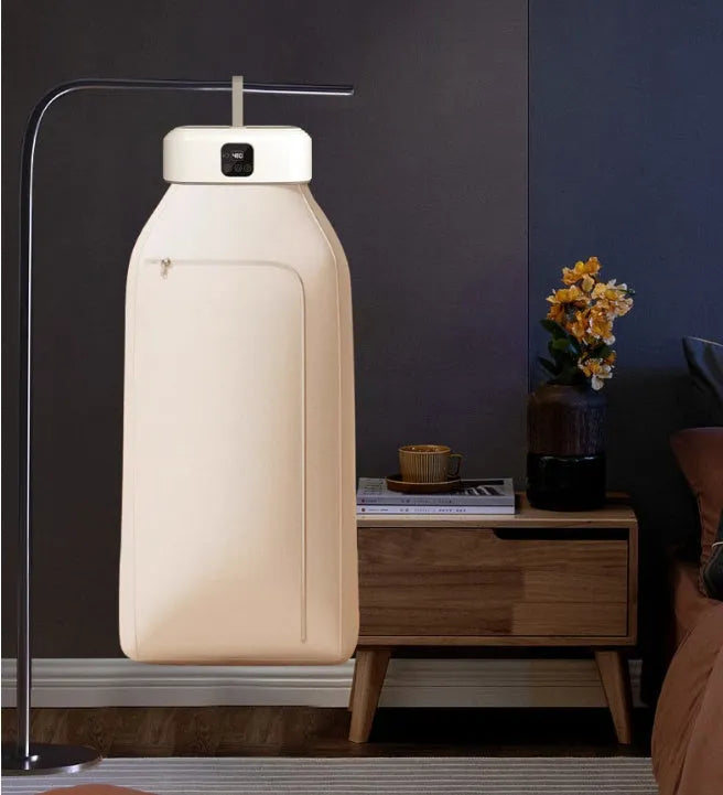 White cylindrical compact laundry drier with remote control on countertop