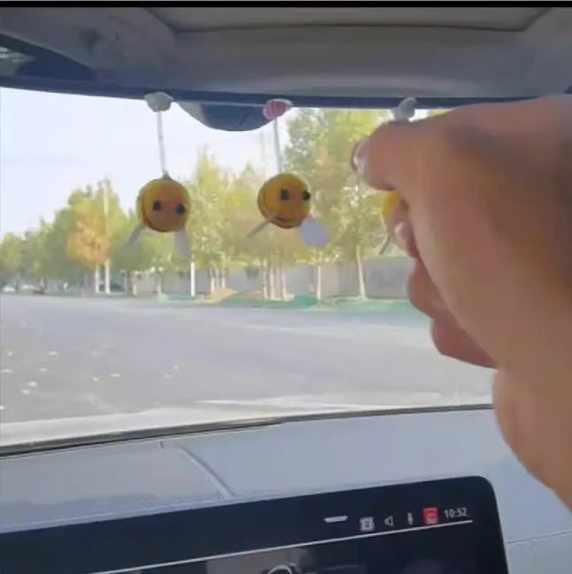 Small, soft, cartoon bee car decoration made from yellow and black fur ball material.