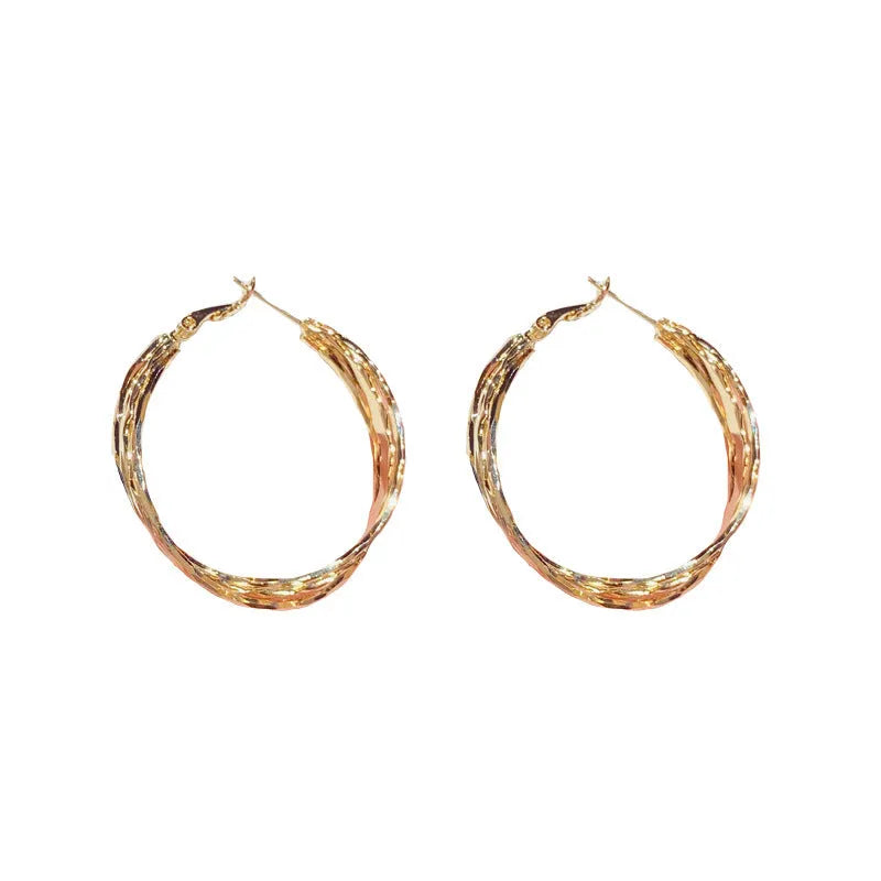 Gold metal twisted earrings with round geometric shape on copper base