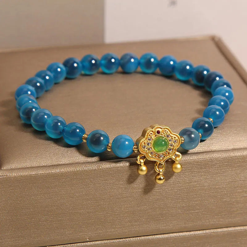 Close-up of a women's blue sugar heart agate safety lock pendant bracelet with crystal links and rhinestone detailing.
