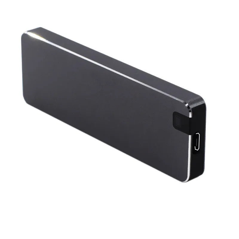 White portable external SSD with metal shell and USB cable next to a laptop.