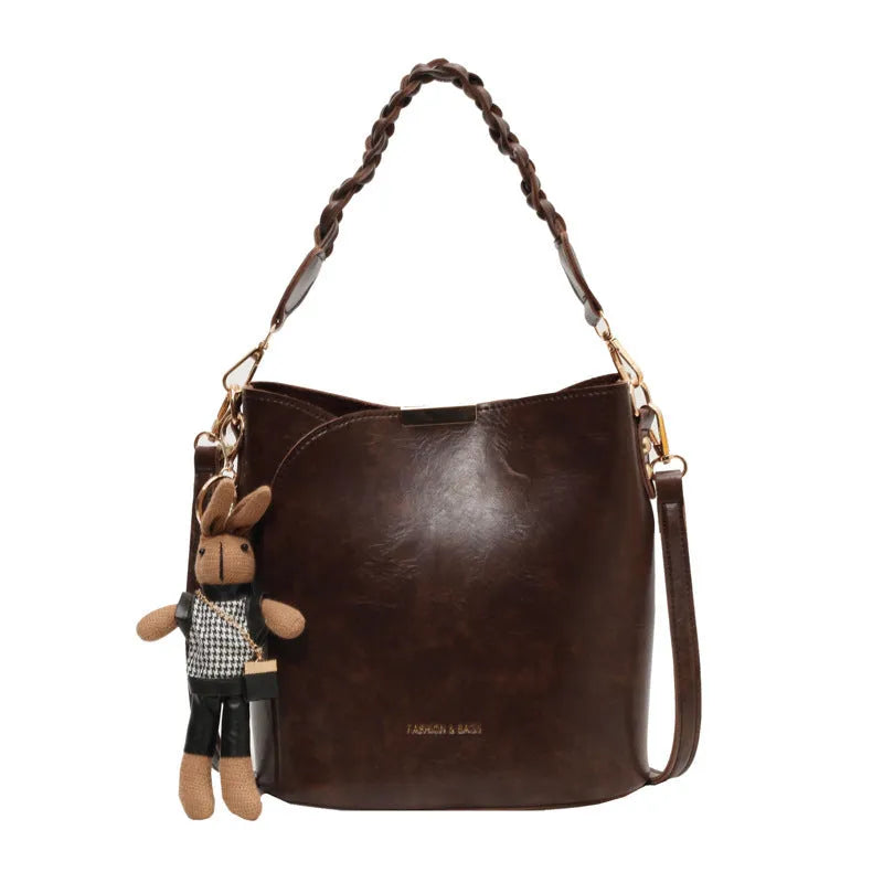 Women's retro PU messenger bag in brown with compact bucket shape, pendant, and double shoulder strap connector