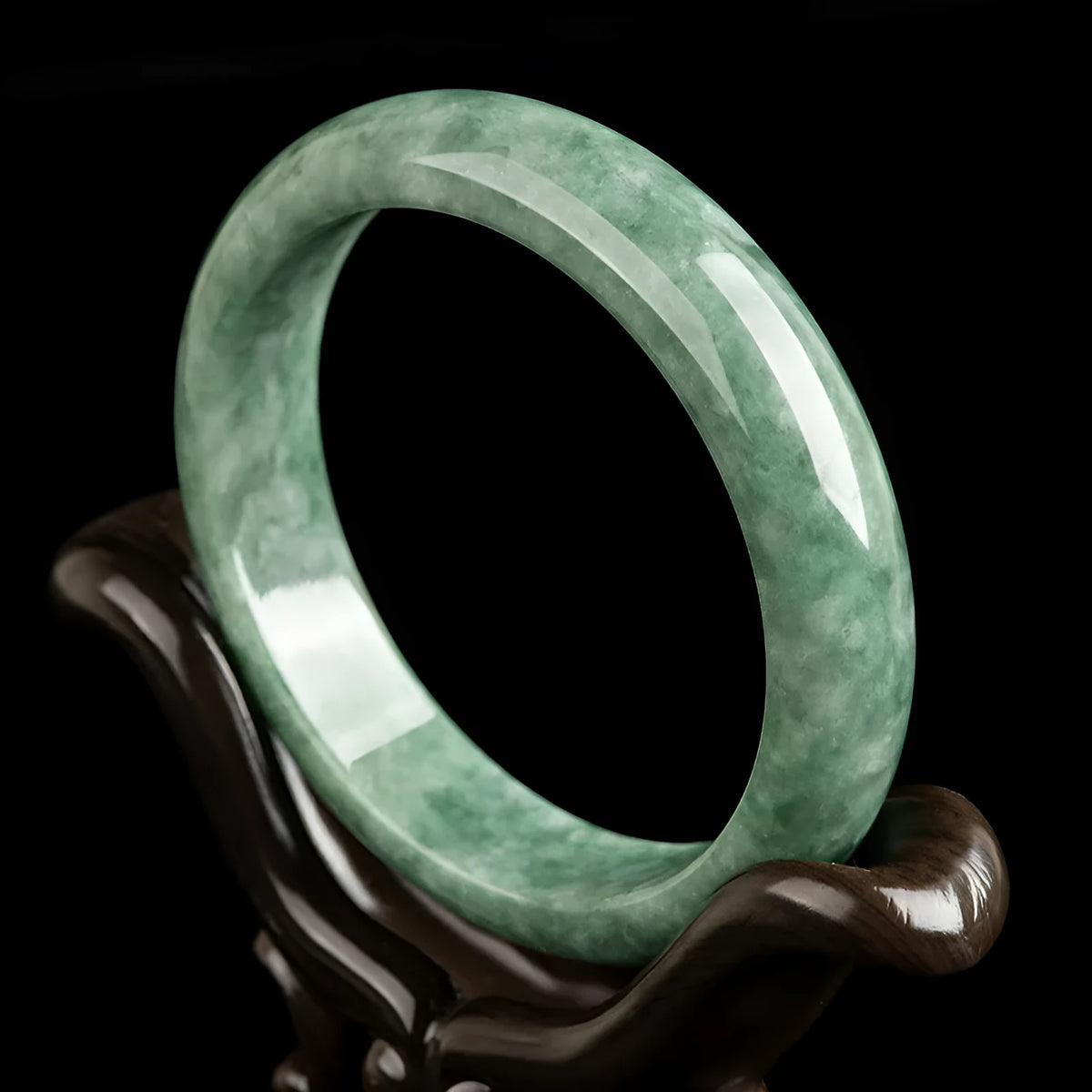 Natural emerald green jade bracelet on wrist, showing simple band style and deep pea green stone colour.