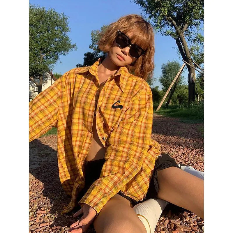 A man or woman wearing a loose-fitting yellow plaid cardigan-style shirt.