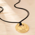 Women's gold alloy oval pendant necklace with braided rope chain on a plain background