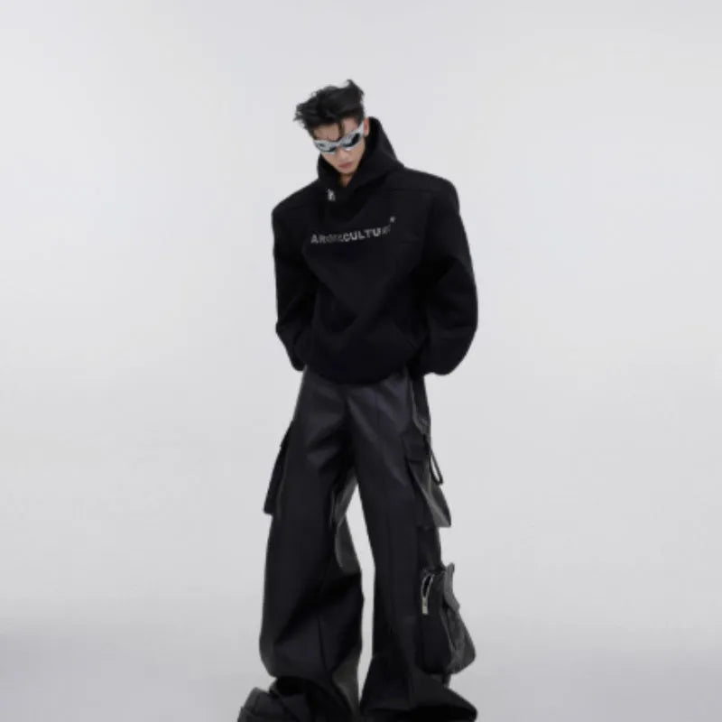 A man's loose black hooded sweater with heavy shoulder pads and a metallic three-dimensional printed design on the front.