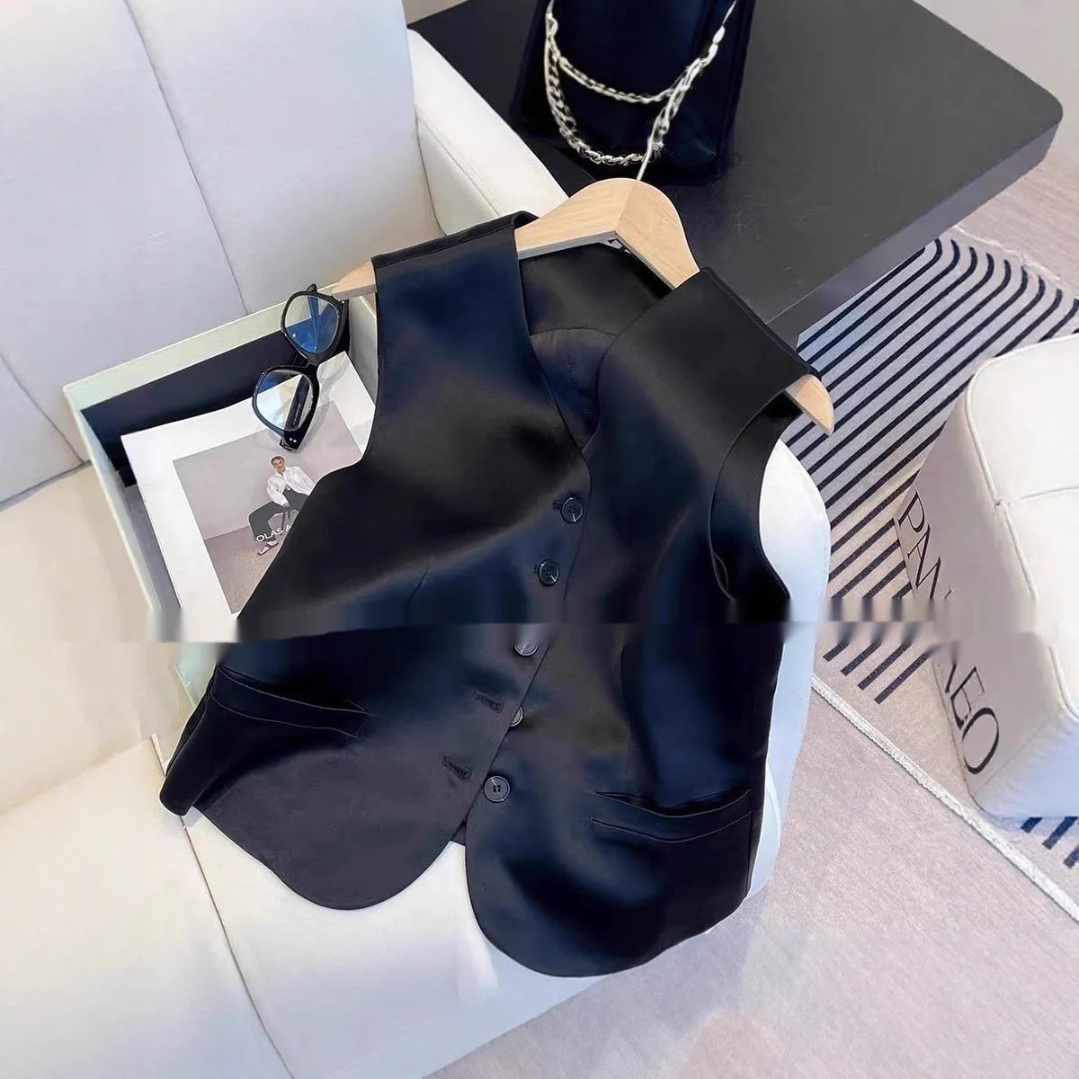 Black sleeveless satin vest for women on a hanger, showing loose fit and normal length.