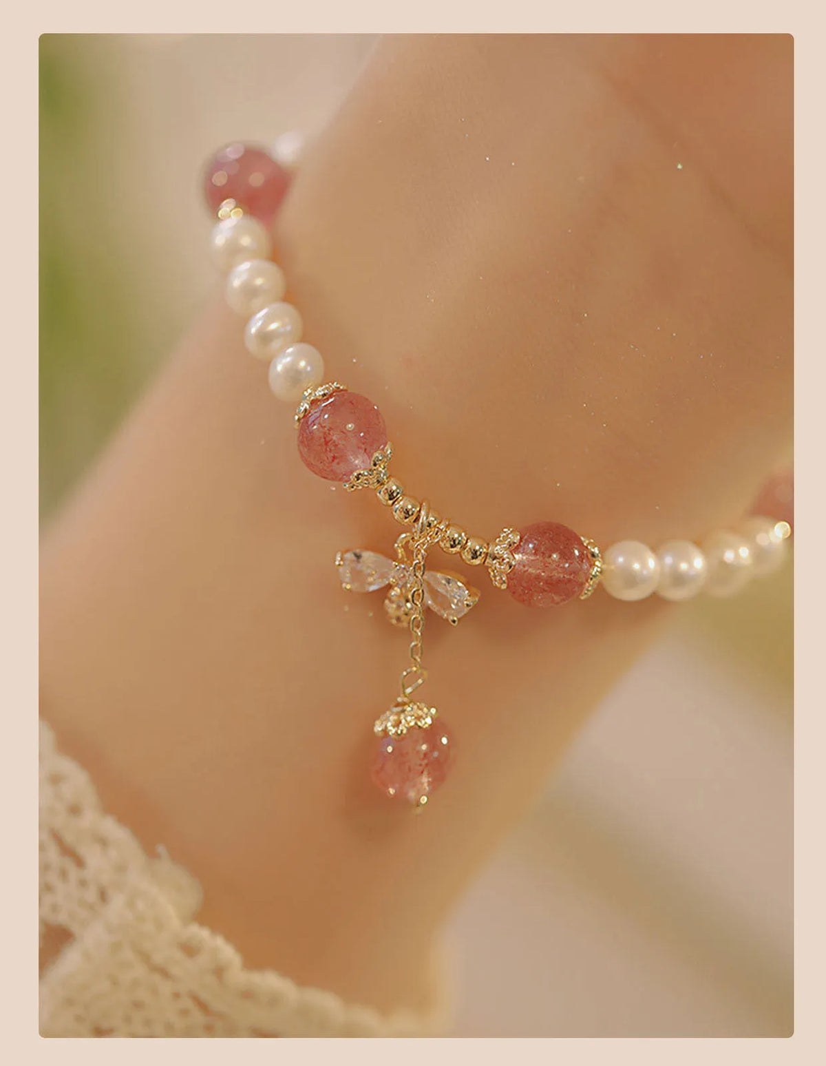 Close-up of a women's hand-strung strawberry quartz crystal bracelet with a decorative bow.