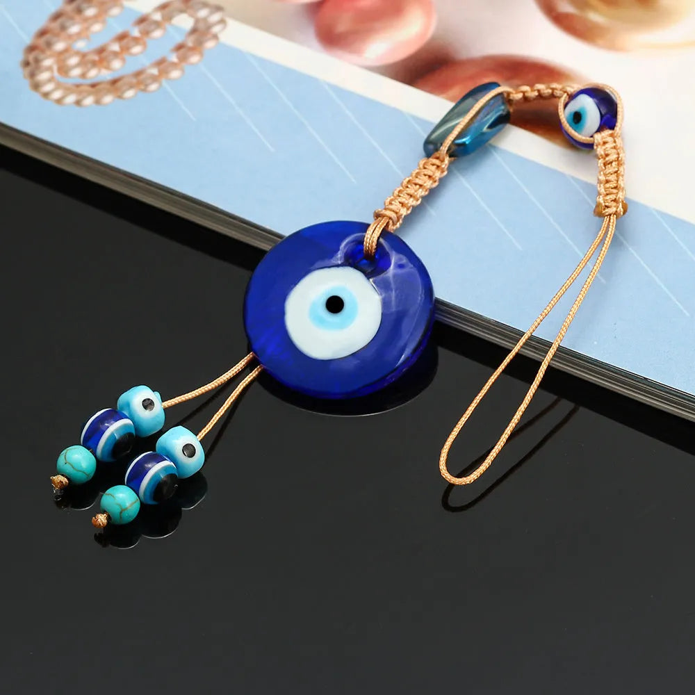 Glass evil eye bead ornament with Turkish blue eye pattern and braided string for wall or car hanging