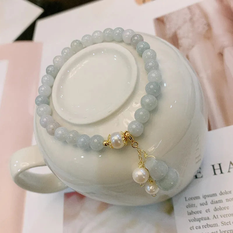 Chinese style jade bracelet with gourd charm and pearl accents on wrist