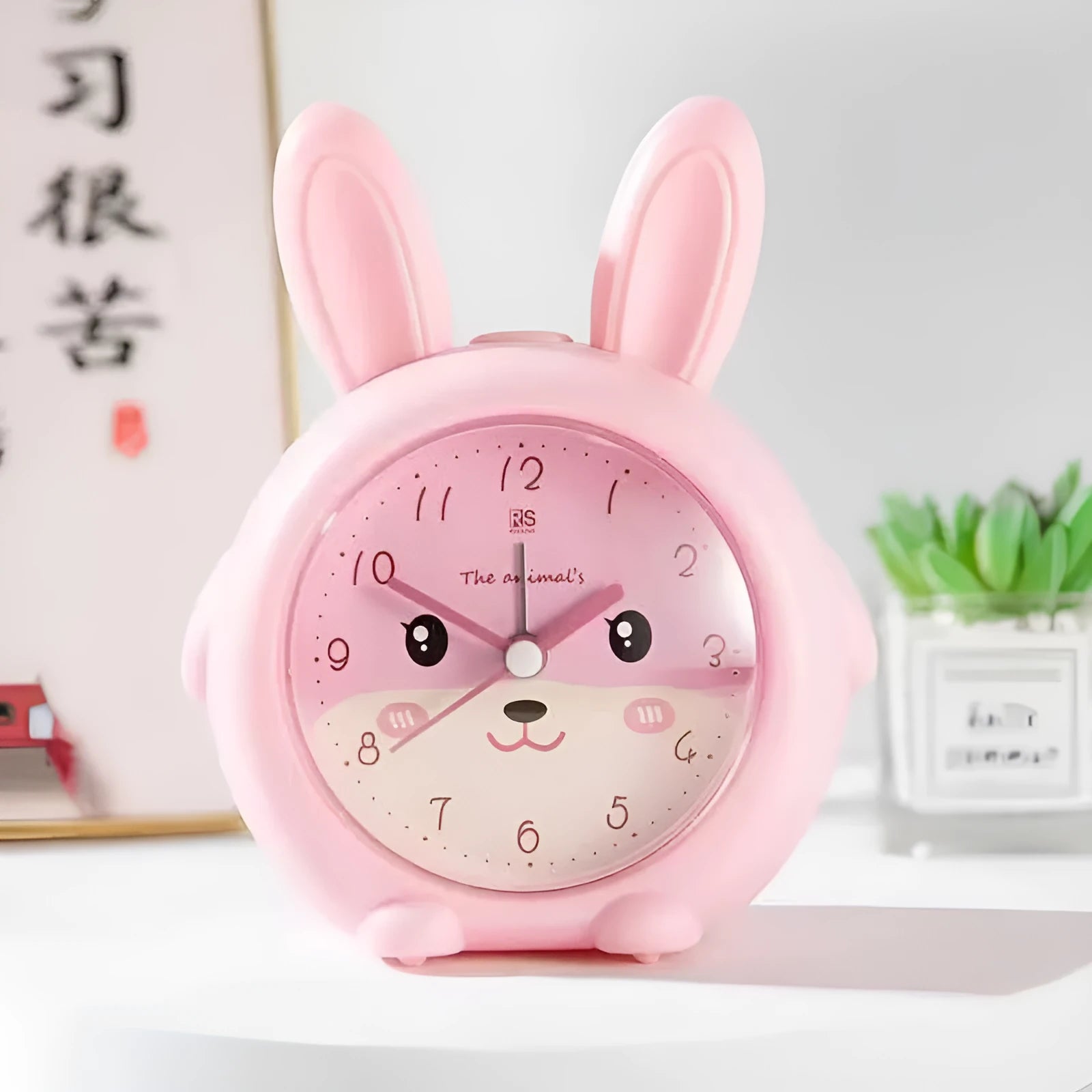 Pink and blue cartoon children's alarm clock with night light on a bedside table