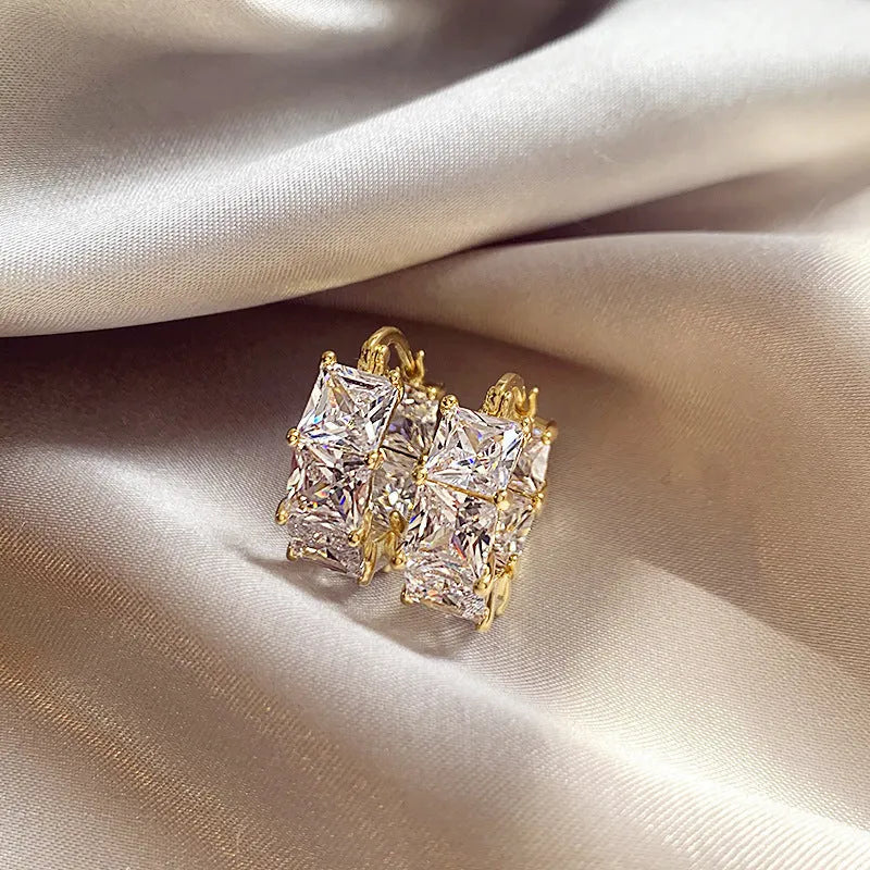 Geometric U-shaped gold tone earrings with round black zircon stone.