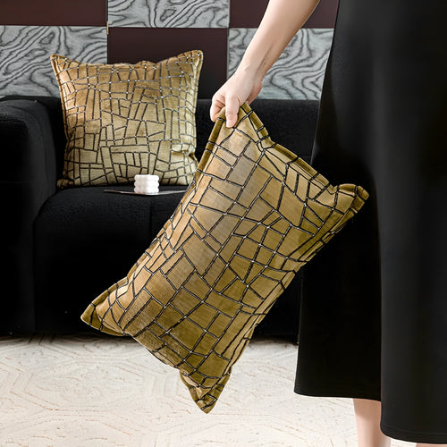 Gold geometric abstract patterned square cushion on a grey sofa.