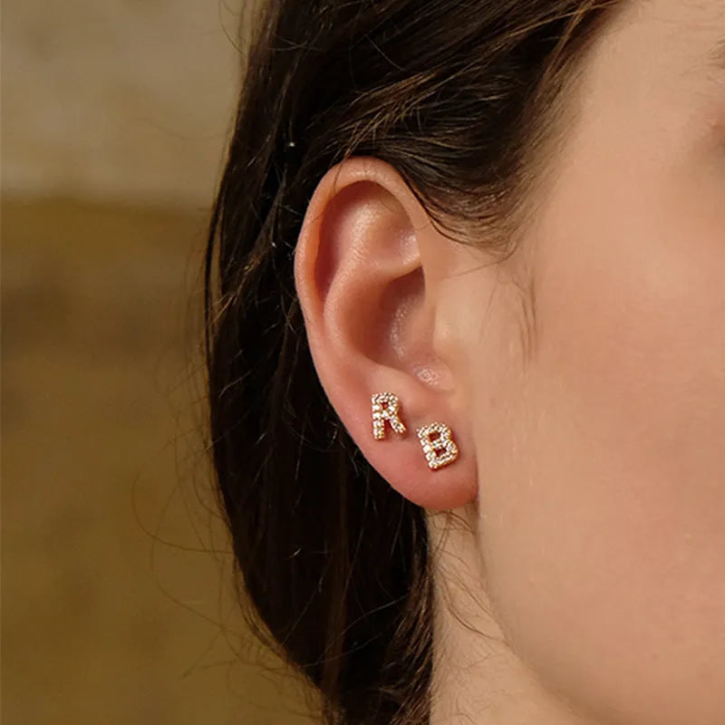 Gold plated brass alphabet letter earrings on a white background, showing zircon detail.