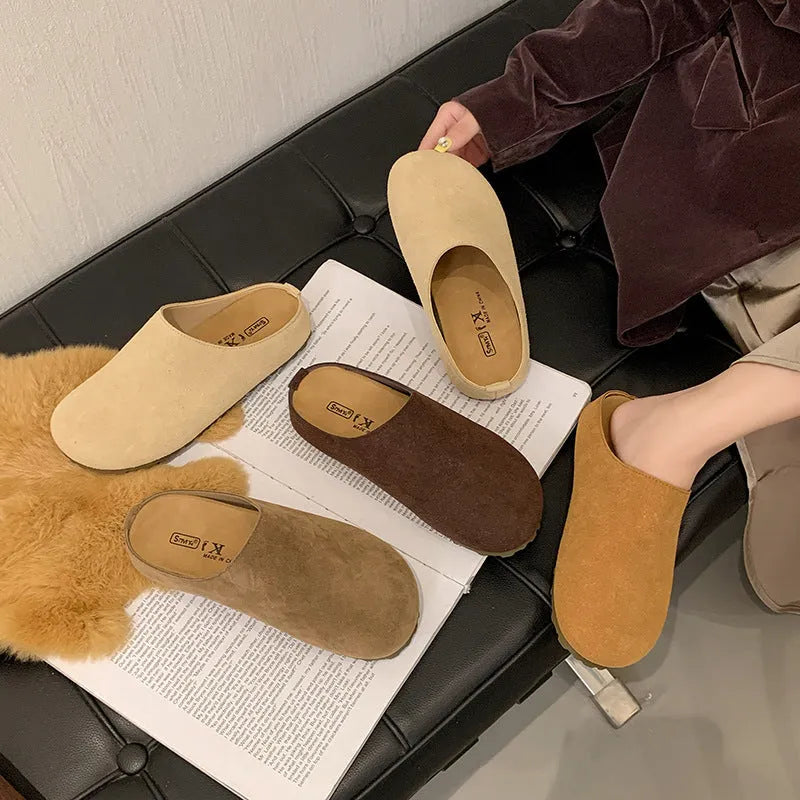 A pair of soft, flat apricot-coloured slip-on slippers with a square toe and microfiber upper on a plain background.