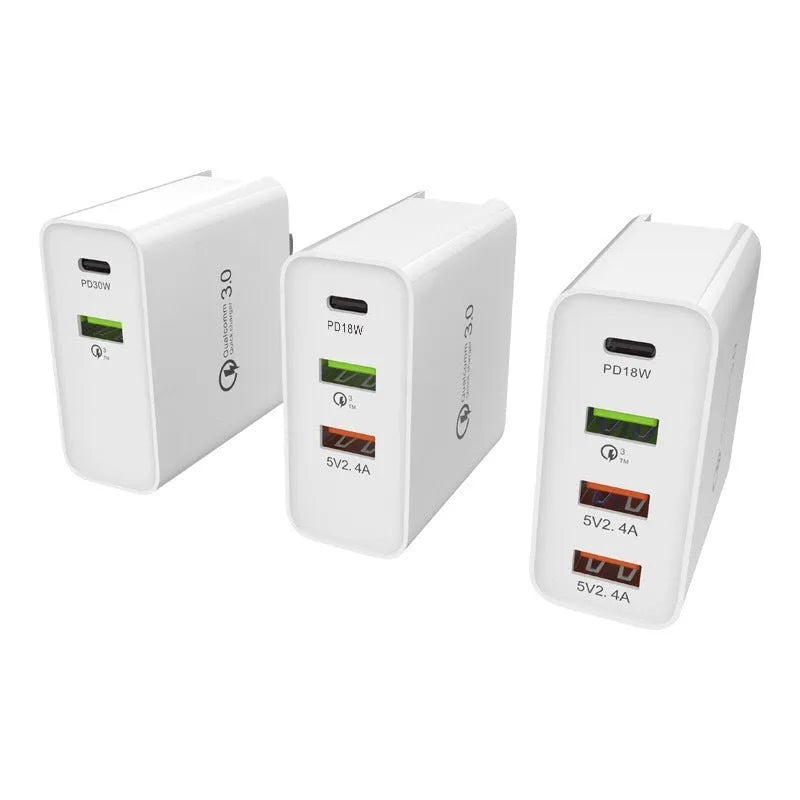White multi-port fast charging adapter with UK plug on a table.