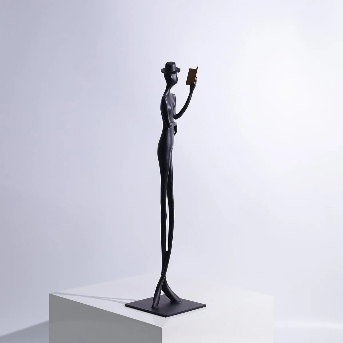 Black aluminium sculpture of reading woman for desktop decoration measuring 51cm tall