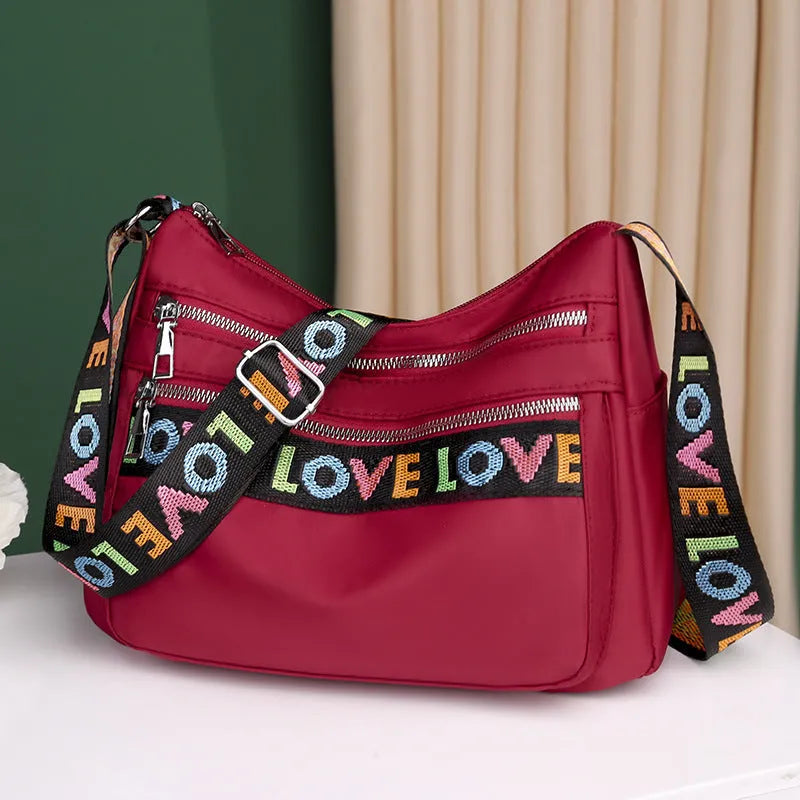 Oxford cloth crossbody shoulder bag in red or black with single strap, multi-pocket large capacity, and letter stitching details