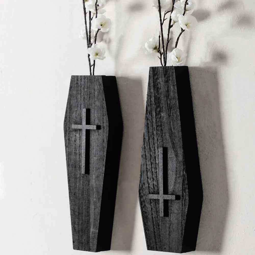 Black wooden cross-shaped wall shelf with space for holding small plants or decorative items.