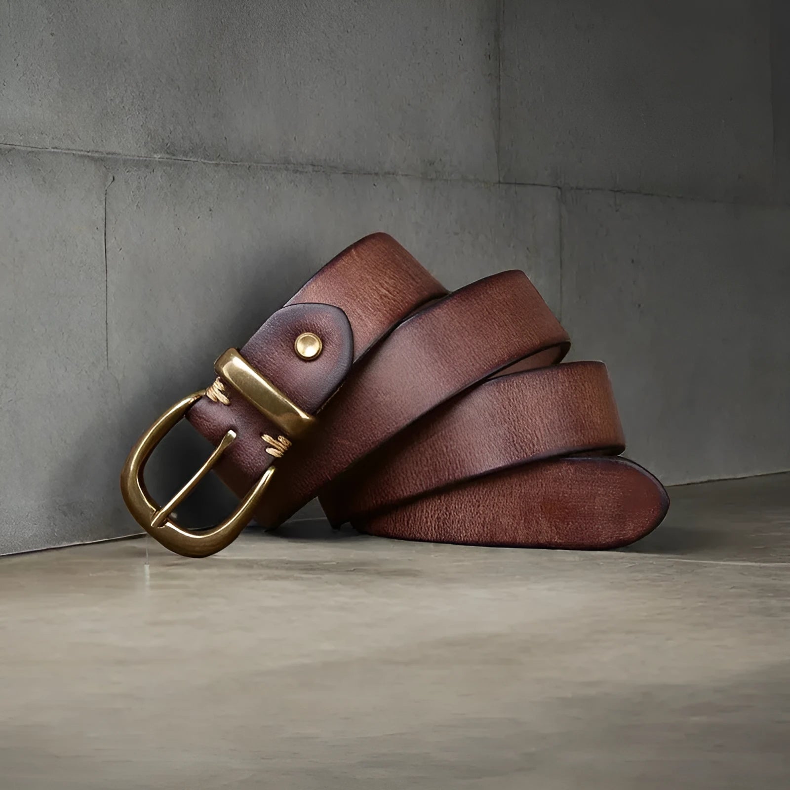 Men's black casual leather belt with a copper pin buckle on a jeans background.
