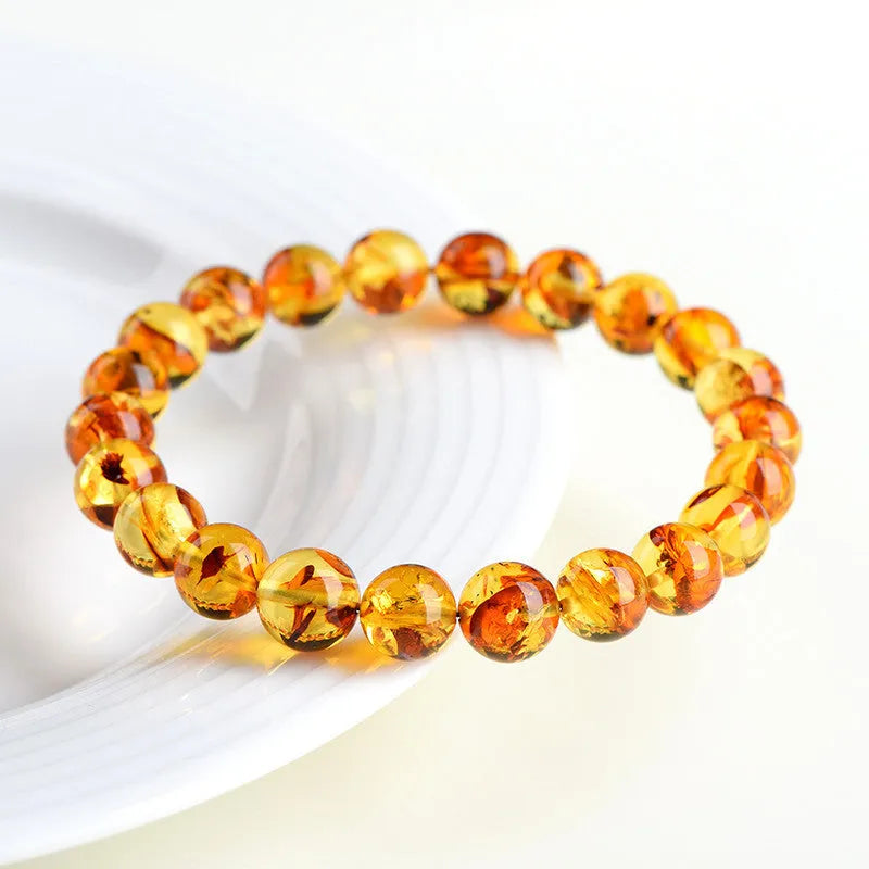 Natural yellow piebald amber bracelet with geometric beads on wrist.