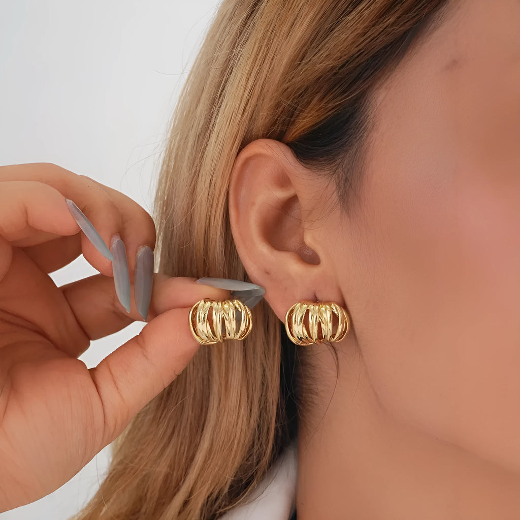 Gold metal ear loops with niche design and metal earrings on white background
