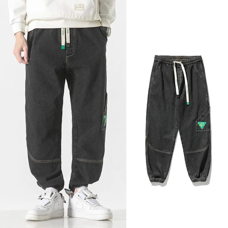 Men's loose-fit tapered cotton trousers in grey showing mid-waist design and tapered leg silhouette