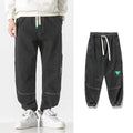 Men's loose-fit tapered cotton trousers in grey showing mid-waist design and tapered leg silhouette