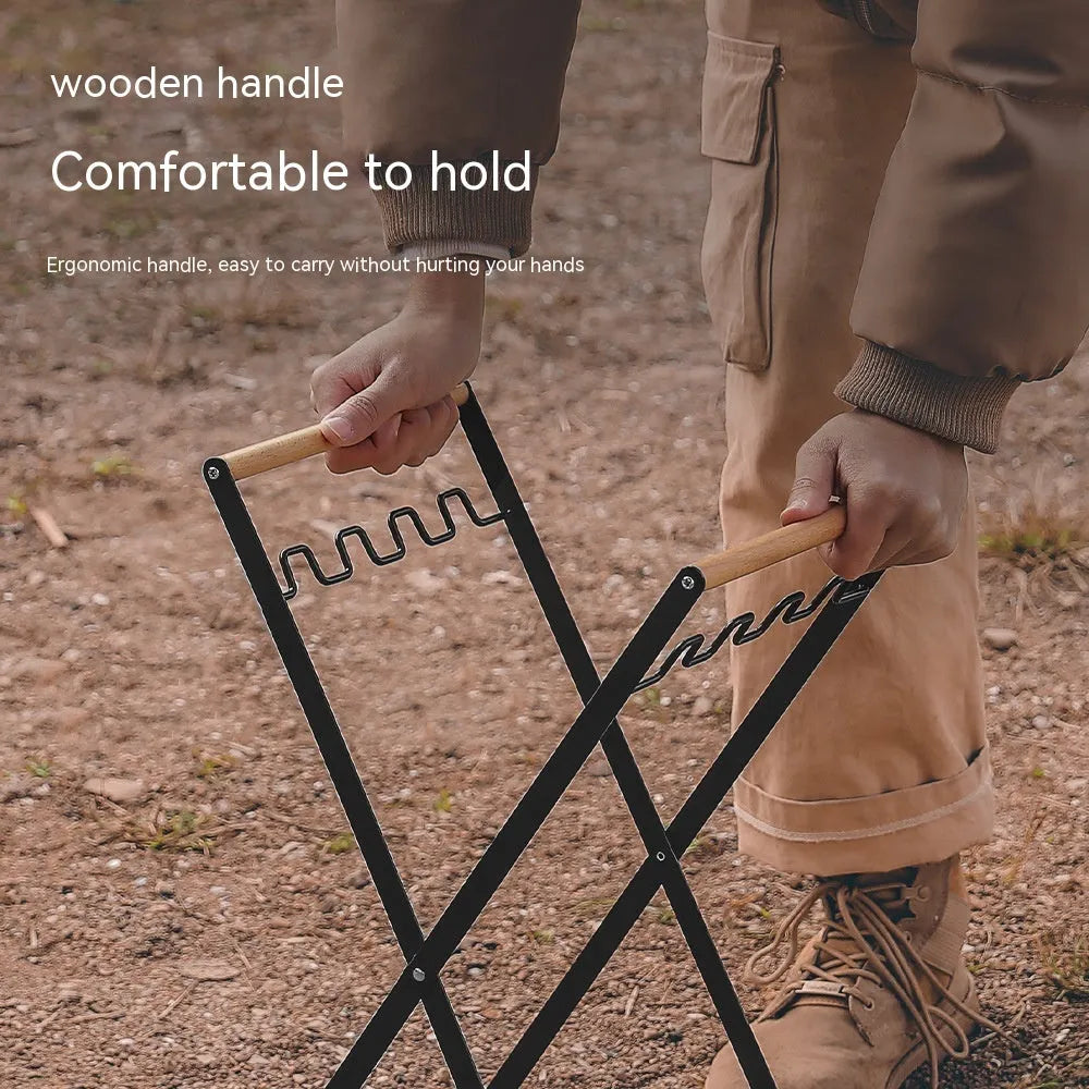 Black iron folding trash rack with wooden handle holding a bin bag outdoors.